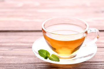 Cup of tea with mint leafs on brown wooden table