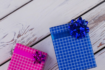 Beautiful gift boxes on wooden background. Two gift boxes wrapped in different colored paper with...