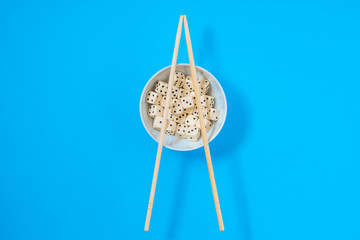 dices in a white bowl with chopsticks on a blue background
