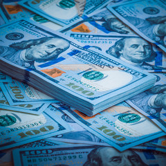 A pack of American dollars on the background of hundred dollar bills. Blue design.