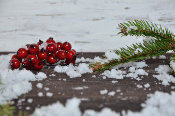 Christmas decoration background: fir branches, cones snow and holly red berries on brown wooden...