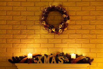 White decorated fireplace with wreath on brick wall background