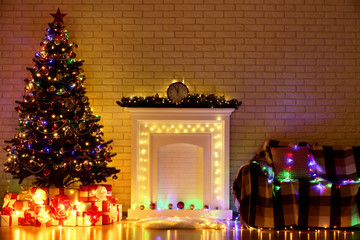 White decorated fireplace near christmas tree and sofa on brick wall background