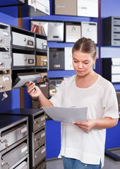 Young woman choosing reliable letterbox in specialty shop
