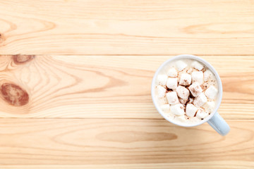 Cappuccino with marshmallows in cup on brown wooden table