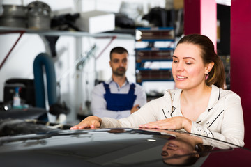 Female client delighting with car after repainting