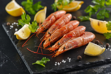 langoustines with spices, lemon and herbs on a black background. Tiger shrimps with spices and lemon.