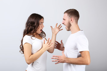Young couple arguing on grey background