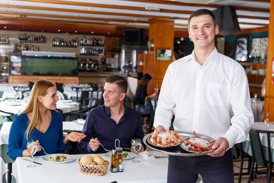 Waiter demonstrating tray of lobsters