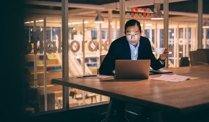 Businessman sitting late night in office working on laptop