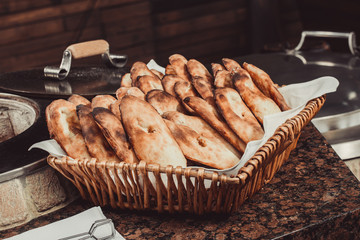Baker making turkish pita bread in tandoor (clay oven). Baking process. Many fresh hot bread in the basket