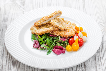 Grilled chicken breasts with sesame, salad with cabbage fat and rucola on light wooden background. Hot Meat Dishes