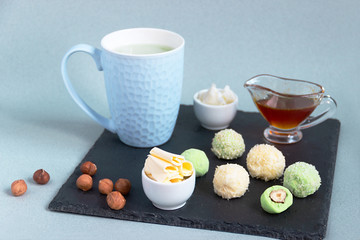 Fat keto peanut butter, cheesecake, matcha balls and keto matcha coconut bulletproof tea in blue cup. keto protein balls and matcha tea recipes ingredients. it works ketogenic diet. blue background