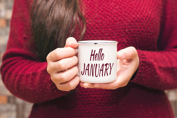 hello january text on cup and woman drinking a coffee 