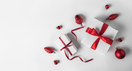 Christmas gift boxes with red ribbon and decoration on white background. Xmas and Happy New Year theme, snow. Flat lay, top view, wide composition