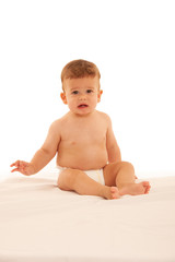 Hapy baby boy in playing on bed isolated over white