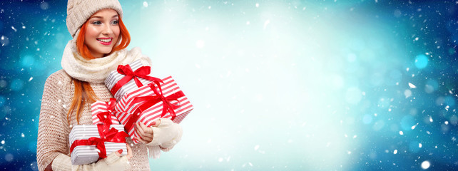 Christmas and New Year holidays. Happy readhead woman with gifts. Shopping woman holding gift boxes on winter background with snow. Sale poster with copy space.