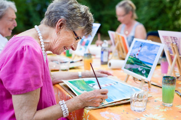 Senior woman smiling while drawing with the group. - obrazy, fototapety, plakaty
