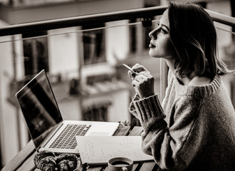 Beautiful young businesswoman working on laptop while sitting outdoors at home. Concept of work with startup business . Image in black and white color style