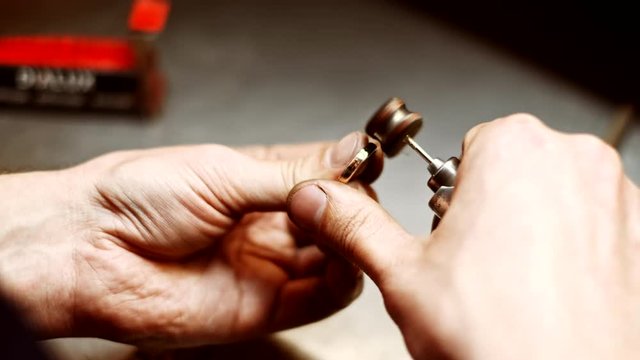 Jeweler polishing gold ring in workshop with professional jewelry tools. Goldsmith working, forming making decoration on silver ring in workplace. Craft jewellery making. Jewelry maker hands close-up.