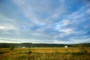 Summer landscape with field, blue cloudy sky and a camping, wide-angle