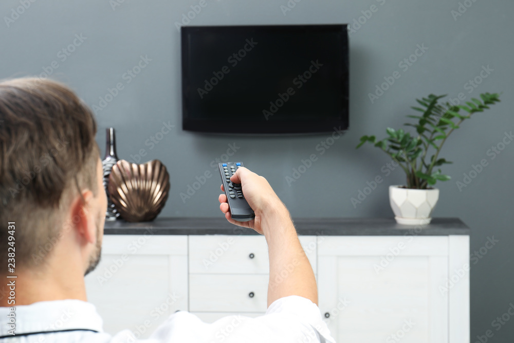 Poster man switching channels on plasma tv with remote control at home