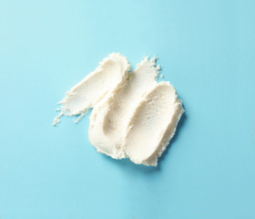 Smear of tasty cream cheese on color background, top view