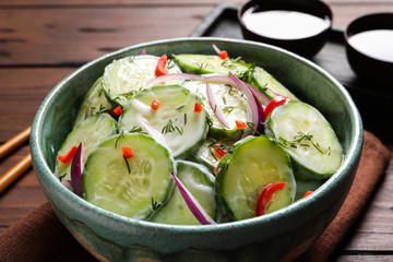 Dish with fresh creamy cucumber salad on wooden table
