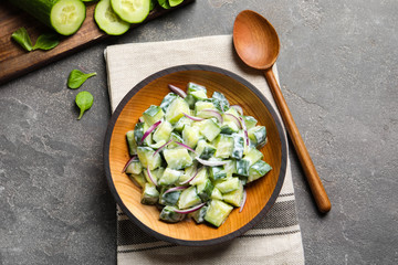 Flat lay composition with wooden plate of creamy cucumber salad on table