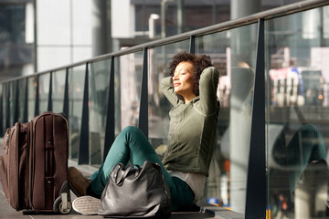 african american travel woman sitting on station floor with bags