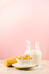 corn with flakes and milk/corn flakes with milk and a corn ear on a pink background with copy space