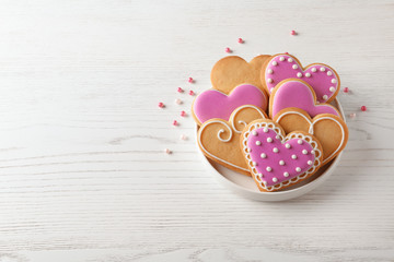 Plate with decorated heart shaped cookies on wooden table. Space for text