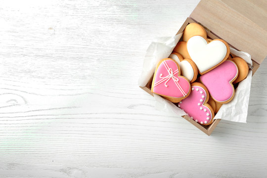 Decorated heart shaped cookies in wooden box and space for text on table, top view