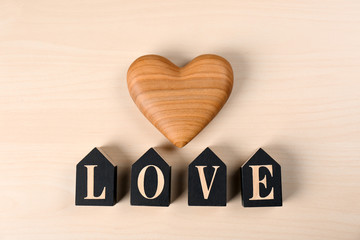Word Love made of decorative letters and heart on wooden background, top view