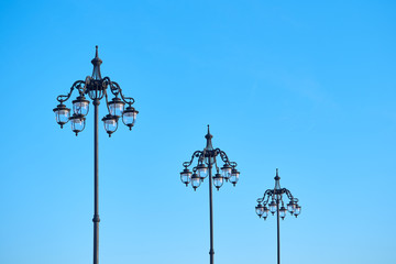 Fototapeta na wymiar Wrought streetlamps on the background of blue sky