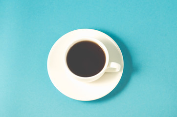 espresso cup on a blue background/white cup with a saucer full of black coffee on a blue background, top view
