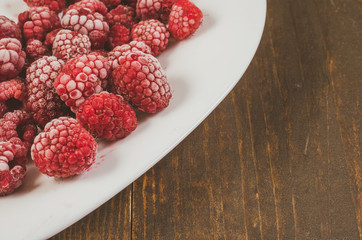 frozen raspberry on a dish/frozen raspberry on a white dish and wooden table, top view and copy space