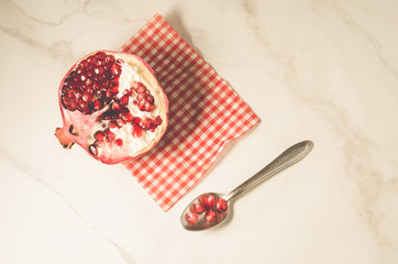 parts of pomegranate on a red napkin and a spoon/parts of pomegranate on a red napkin and a spoon on a white background, top view