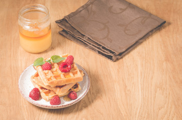 Waffles With raspberry in plate. Breakfast/Homemade waffles with raspberry in plate, honey on a wooden table, selective focus
