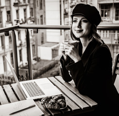Beautiful young businesswoman working on laptop while sitting outdoors at home. Concept of work with startup business . Image in black and white color style