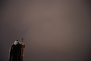 A monument to the priest on the background of dark sky with space for writing