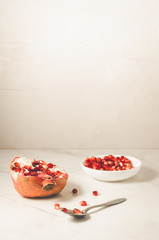 white table of grenades fruit, the purified red seeds of pomegranate in a bowl/grenades fruit, purified red seeds of pomegranate in a white bowl on a white background with copy space