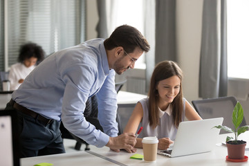 Obraz premium Friendly mentor explaining task smiling young female employee, teacher helping, consulting student, colleagues working together at same task, brainstorm, discussing ideas, online project