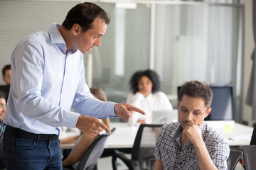 Angry boss scolding frustrated incompetent employee at workplace, dissatisfied leader shouting,...