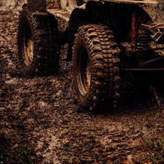 Fototapeta na wymiar Extreme 4x4 auto adventure. Car wheels on steppe terrain splashing with dirt. Car racing offroad. Offroad car in action. Dirty car drive on high speed. SUV or offroader on mud road