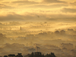Bergamo, Italy. Amazing landscape of the town covered by the fog arising from the plain in fall season