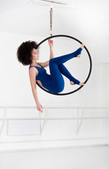 Woman hanging in aerial ring, isolated on white