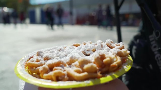 Young woman eating funnel cake outdoors in city