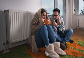 Couple sitting beside radiator and freezing