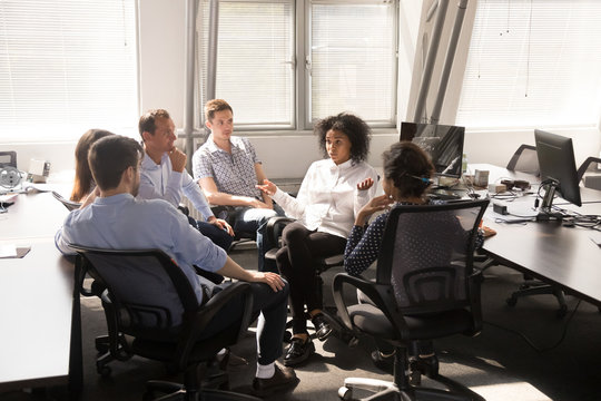 Serious African American female leader, coach talking with employees at company meeting, boss discussing business strategy, plan with multiracial team office workers, giving instructions, report news